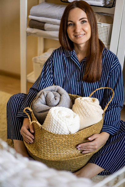 Portrait of happy young domestic woman in pajamas posing with straw basket for linens storage - Valokuva, kuva