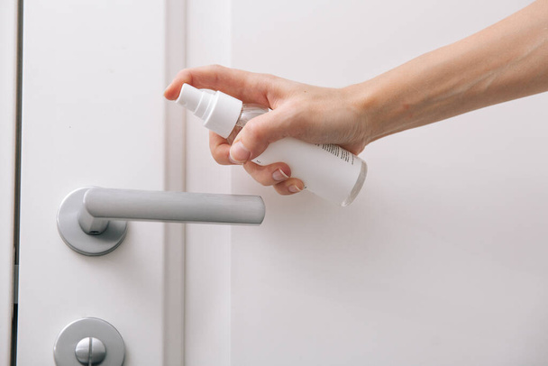 Cleaning white door handles with an antiseptic wet wipe and sanitizer spray. Disinfection in hospital and public spaces against corona virus. Woman hand using towel for cleaning home room door link - Фото, изображение