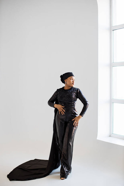 African woman in hijab and black evening wear posing indoors - Photo, Image