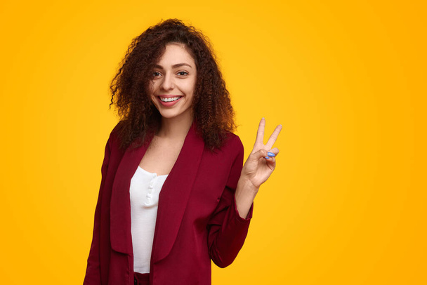Smiling woman showing peace sign in studio - Foto, immagini