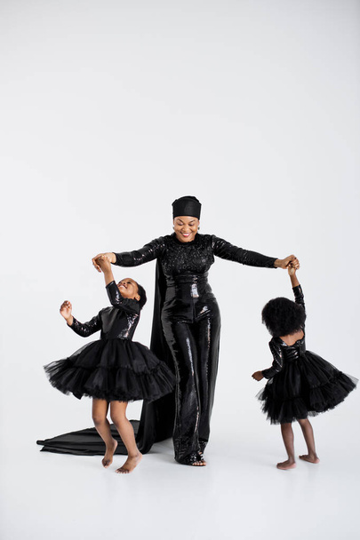Woman with daughters in elegant clothes dancing indoors - Foto, afbeelding