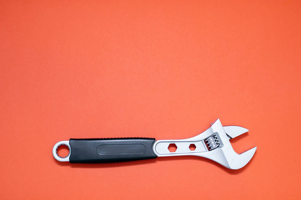 Modern adjustable wrench on an orange background with free space for text. The concept of a tool for repair or construction. Special tool for repairing pipes and clamping nuts with adjustment - Foto, immagini