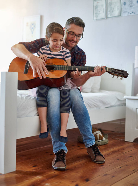 Hanno molto in comune. Girato di una bambina che suona la chitarra con suo padre. - Foto, immagini