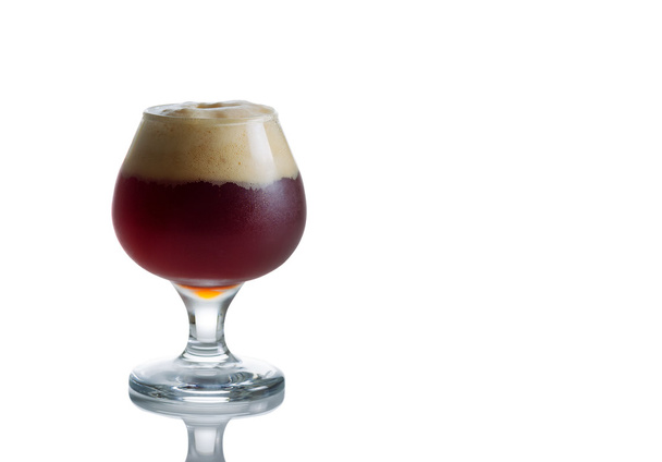 üveg talpas pohár tele van friss barna sör, fehér  - Fotó, kép