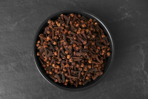 Bowl of aromatic dry cloves on black table, top view - Valokuva, kuva