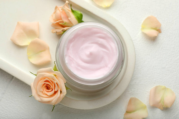 Jar of organic cream and roses on white table, flat lay - Фото, изображение