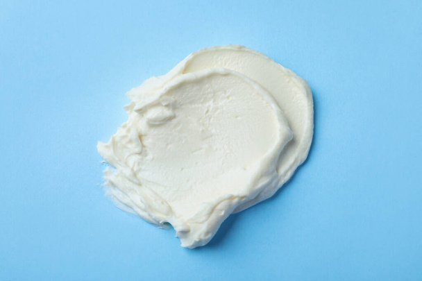 Smear of delicious cream cheese on light blue background, top view - Foto, imagen