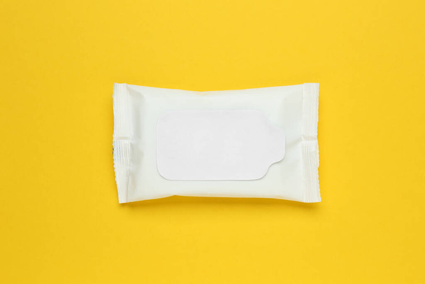 Natte doekjes flow pack op gele achtergrond, bovenaanzicht - Foto, afbeelding