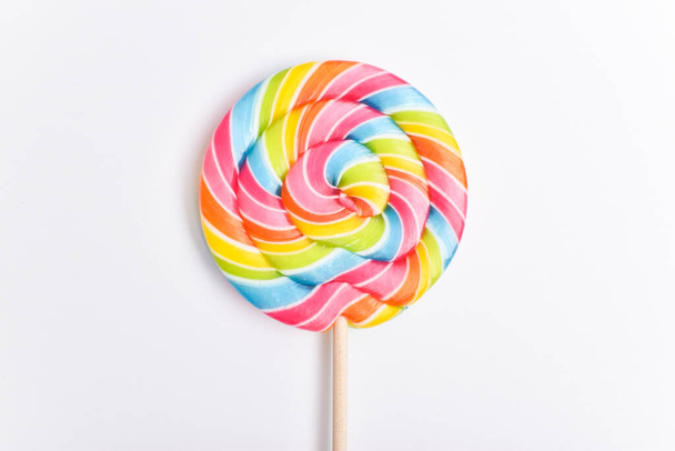 A colored lollipop on a stick. Sweet dessert. Confectionery background. Copy space. Flat lay, top view. - Photo, Image