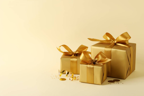 Beautifully wrapped gift boxes and confetti on beige background, space for text - Фото, изображение