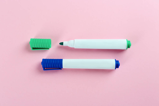 Two colorful markers on pink background, flat lay. School stationery - Φωτογραφία, εικόνα