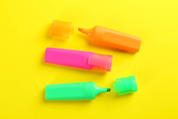 Colorful markers on yellow background, flat lay. School stationery - Fotoğraf, Görsel