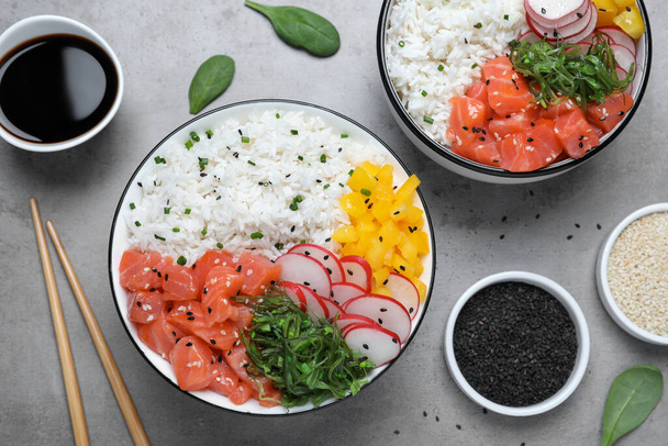 Delicious poke bowls with salmon and vegetables served on light grey table, flat lay - Zdjęcie, obraz