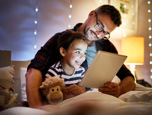 She loves story time with daddy. Cropped shot of a father reading his young daughter a bedtime story on a tablet. - Foto, imagen