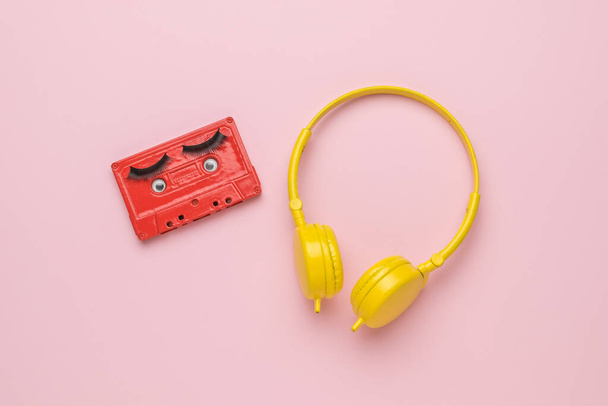 Yellow headphones and a red tape recorder with eyes on a pink background. Creative image. The concept of analog sound recording. Flat lay. - Foto, afbeelding