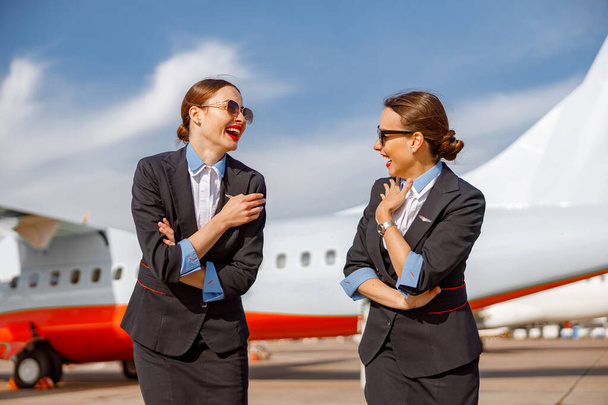 Wesołe stewardessy rozmawiają i śmieją się na lotnisku - Zdjęcie, obraz
