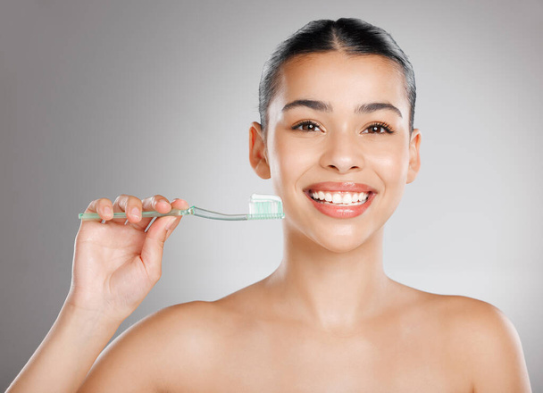 Appelez ça une assurance pour vos dents. Plan studio d'une jolie jeune femme se brossant les dents sur un fond gris. - Photo, image