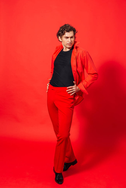 Portrait of a tall handsome man dressed in red shirt posing on the red background. - Foto, Bild