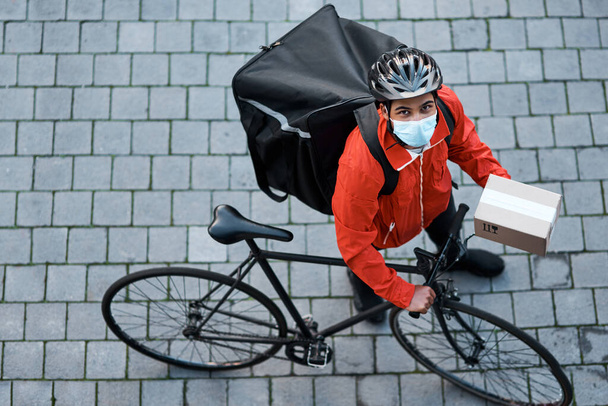 Safety is our highest priority. Shot of a masked man out with his bicycle to do a delivery. - Photo, image