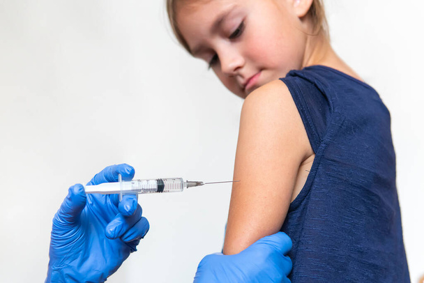 女の子は医者のオフィスで注射を恐れている。少女はワクチン接種の痛みと恐怖を経験しています. - 写真・画像