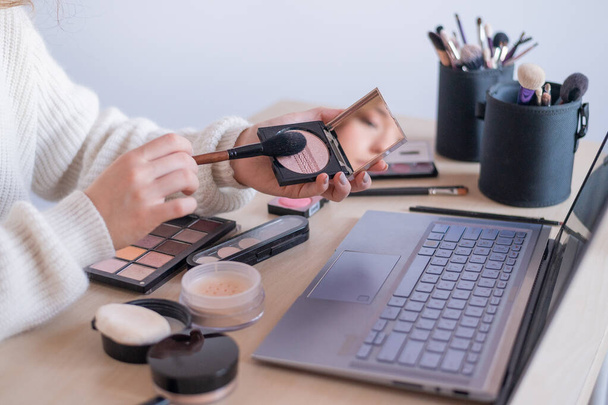 Online makeup tutorials. A woman watches a video training herself as a makeup artist on a laptop - Fotó, kép