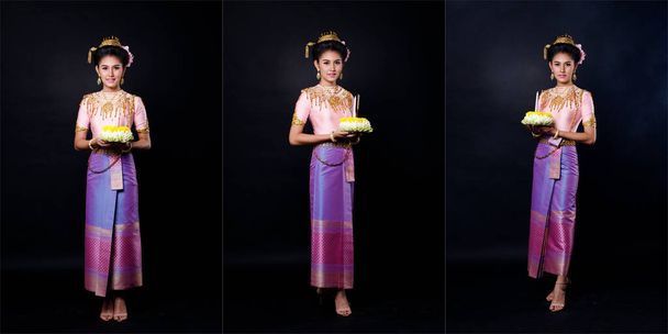 Vestido Loykrathong de traje tradicional tailandês ou sudeste da Ásia vestido de ouro na mulher asiática com decoração stand expressar sentindo sorriso feliz para Loy Krathong flutuante festival sobre fundo preto - Foto, Imagem
