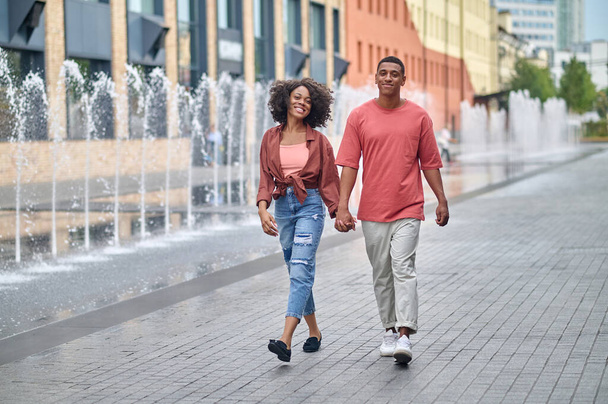 Dark-skinned man and woman holding hand walking - Fotografie, Obrázek