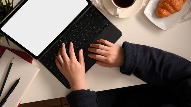 Топ-снимок женщины-фрилансера, работающей на планшетном компьютере и ищущей работу в Интернете на веб-сайте в своем домашнем рабочем пространстве. - Фото, изображение