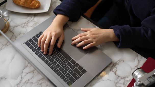 Imagen de cerca de una estudiante universitaria haciendo su tarea en línea en la computadora portátil portátil en su espacio de trabajo en casa. - Foto, imagen