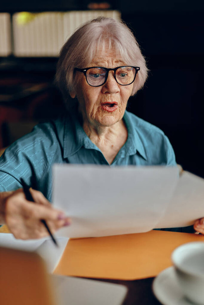Portrait of an elderly woman sitting in a cafe with a cup of coffee and a laptop Freelancer works unaltered - Photo, Image