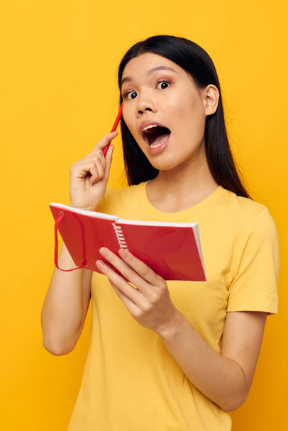 woman in a yellow t-shirt red notebook training yellow background unaltered - Фото, зображення