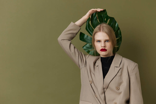 портрет женщины зеленый пальмовый листок пальто яркий макияж студия модель без изменений - Фото, изображение