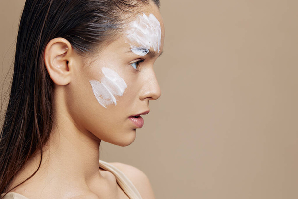 kobieta pielęgnacja skóry przy użyciu białej maski na twarzy beżowe tło - Zdjęcie, obraz