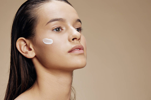 woman cream on cheek posing cosmetics to clean skin isolated background - Zdjęcie, obraz