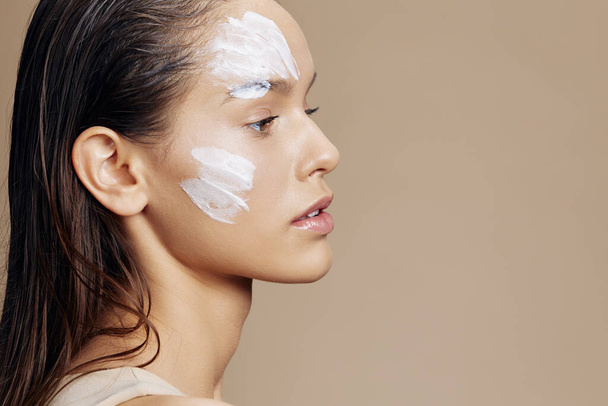 brunette hand near face cream rejuvenation charm close-up make-up - Foto, Imagen