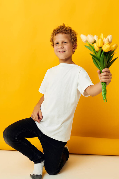 Cute little boy with yellow flowers posing childhood fun yellow background unaltered - Foto, immagini
