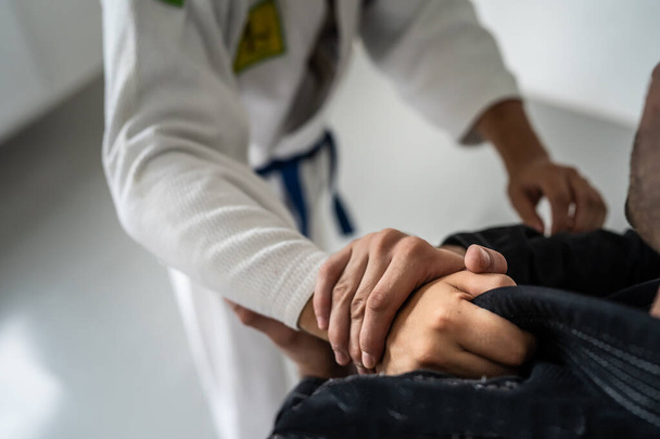 Brazilský Jiu Jitsu BJJ zblízka na ruce a uchopení na kimono gi během tréninku nebo ušetření bojových umění koncept - Fotografie, Obrázek