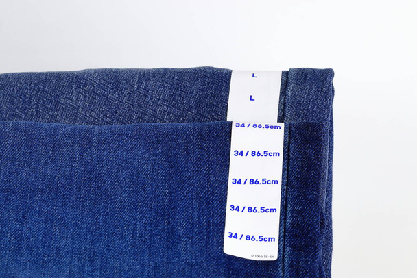 Jeans blu denim con etichetta, collezione jeans impilati con etichetta taglia, taglia tag su jeans blu denim pantaloni. - Foto, immagini
