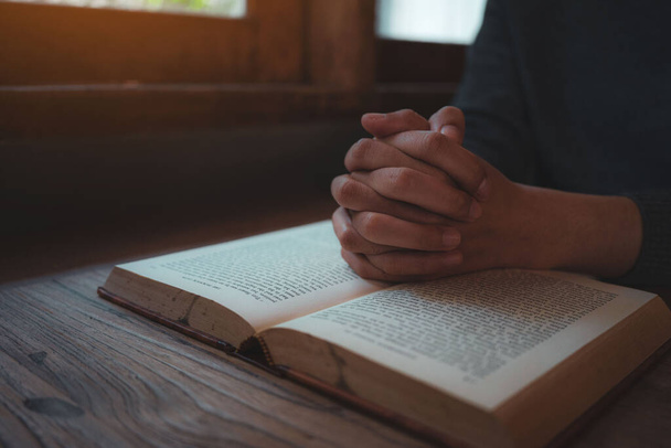 Keresztény nők olvassák a bibliát. Kezek összehajtogatva imában egy Szent Biblián a fa asztalon - Fotó, kép