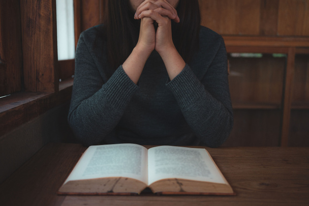 Yakın plan Hıristiyan kadınlar İncil okur. Elleri katlanmış, kutsal bir İncil 'in üzerinde, ahşap bir masanın üzerinde. - Fotoğraf, Görsel