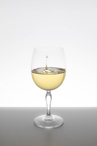 białe wino spadające w szklance na białym tle - Zdjęcie, obraz