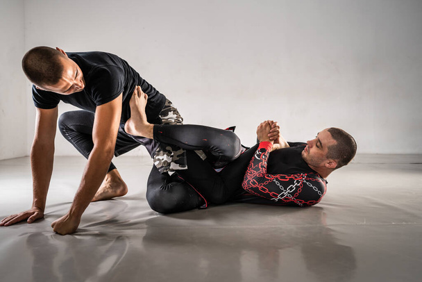 Бразильський джіу джісу джисту бдж ні-гі тренування з вирівнювання два спортсмени буріння техніки або спаринг в гімнастичній академії атака на позиції гель-хук - Фото, зображення