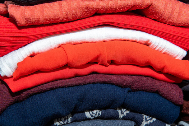 Vêtements empilés dans différentes couleurs dans la garde-robe - Photo, image