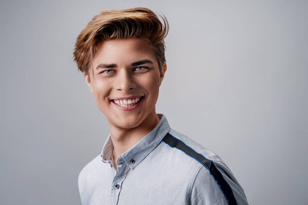 portrait of handsome young guy wearing shirt while looking at camera and smiling Stylish hairstyle.  - Φωτογραφία, εικόνα