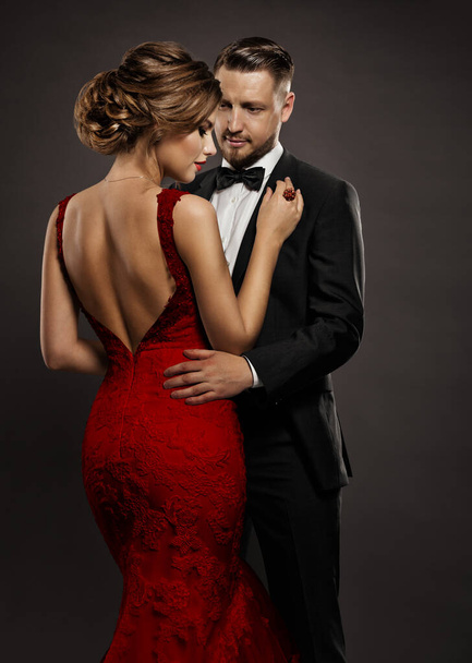 Fashion Wedding Couple in Love. Beauty Woman in Sexy Dress with Naked Back and Handsome Man in Black Suit. Elegant Gentlemen and Lady over Dark Gray Background - Foto, imagen