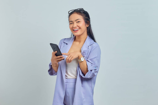 Πορτρέτο της χαρούμενης νεαρής Ασιάτισσας που χρησιμοποιεί το κινητό τηλέφωνο απομονώνονται σε λευκό φόντο - Φωτογραφία, εικόνα