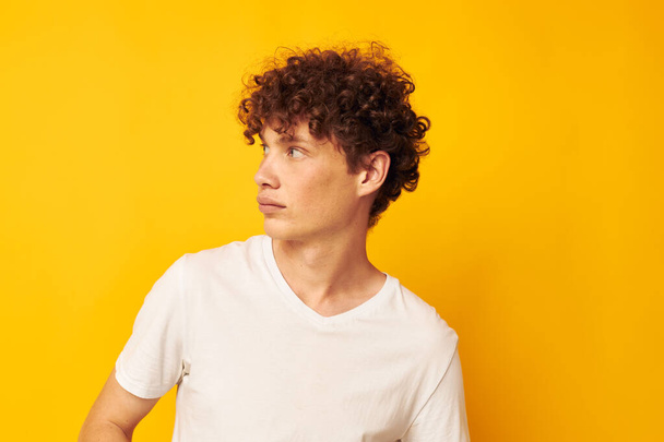 curly red-haired guy in a white t-shirt on a yellow background - Fotografie, Obrázek