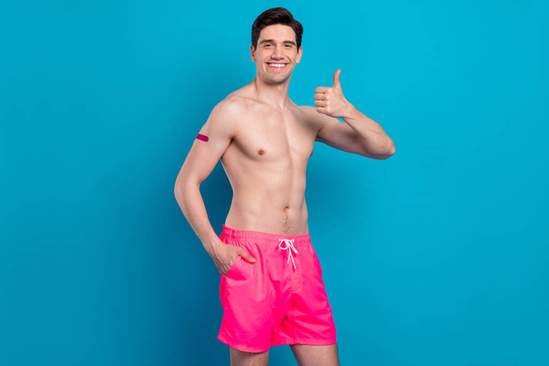 Photo of cheerful cute young man naked torso successful vaccine done showing thumb up smiling isolated blue color background - Fotografie, Obrázek