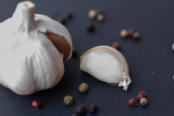 Close-up macro shot of a garlic in a dark background surrounded by peppercorns - Fotó, kép