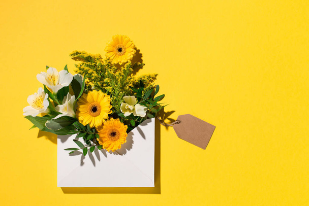 Γιορτινή σύνθεση λουλουδιών. Κίτρινα και λευκά λουλούδια σε χάρτινο κίτρινο φόντο. Άνοιξη, Πασχαλινή κάρτα. Επίπεδο lay, πάνω όψη, αντιγραφή χώρου. - Φωτογραφία, εικόνα
